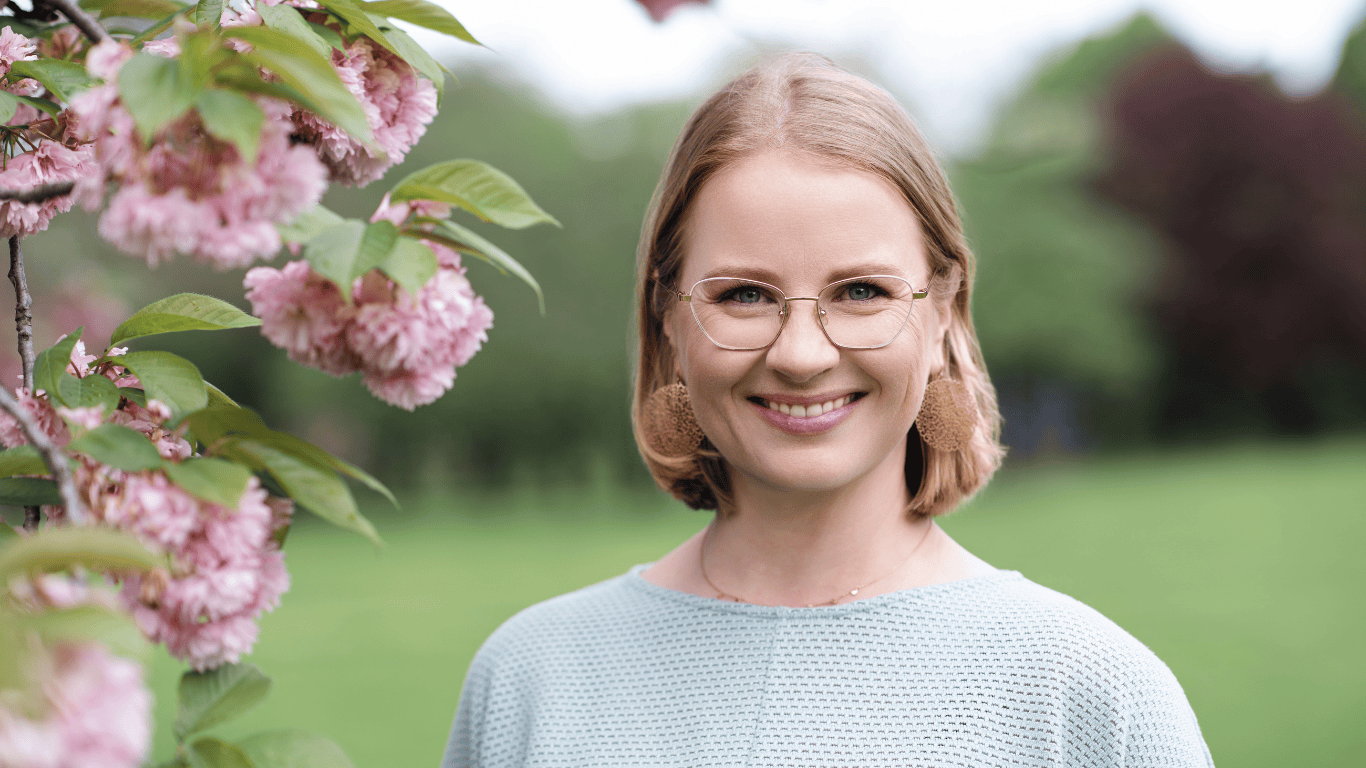 Portrait von Juliane Krumbiegel, Gründerin von Mama Mojo, lächelnd vor einem blühenden Kirschbaum im Grünen – Symbol für Leichtigkeit, Lebensfreude und Selbstfürsorge im Mama-Alltag.