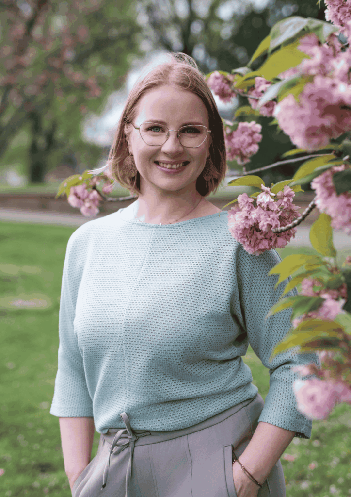 Portrait von Juliane Krumbiegel, Gründerin von Mama Mojo, im Park zwischen blühenden Kirschzweigen – Symbol für Leichtigkeit, Selbstfürsorge und Lebensfreude im Mama-Alltag.