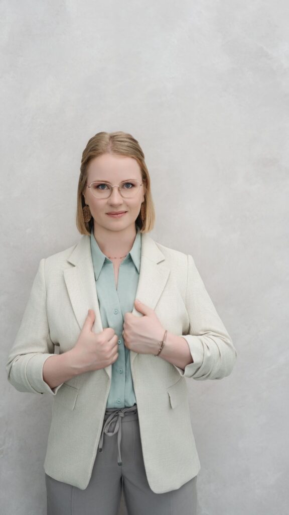 Business-Portrait von Juliane Krumbiegel, Gründerin von Mama Mojo, mit beigem Blazer und grünem Oberteil – Mentorin für Mütter rund um Mental Load, Selbstfürsorge und Familienbalance.