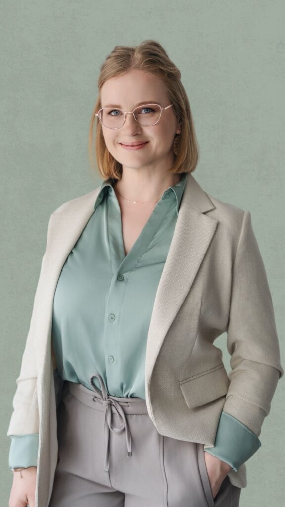 Business-Portrait von Juliane Krumbiegel, Gründerin von Mama Mojo, mit beiger Jacke und grüner Bluse – Mentorin für Mütter rund um Mental Load, Selbstfürsorge und Familienbalance.